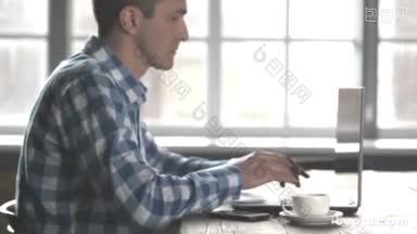 穿着休闲装的商务人士一边喝着咖啡，一边用笔记本<strong>电脑工作</strong>